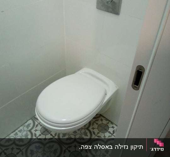 אסלה עם לחצן הדחה על קיר לבן